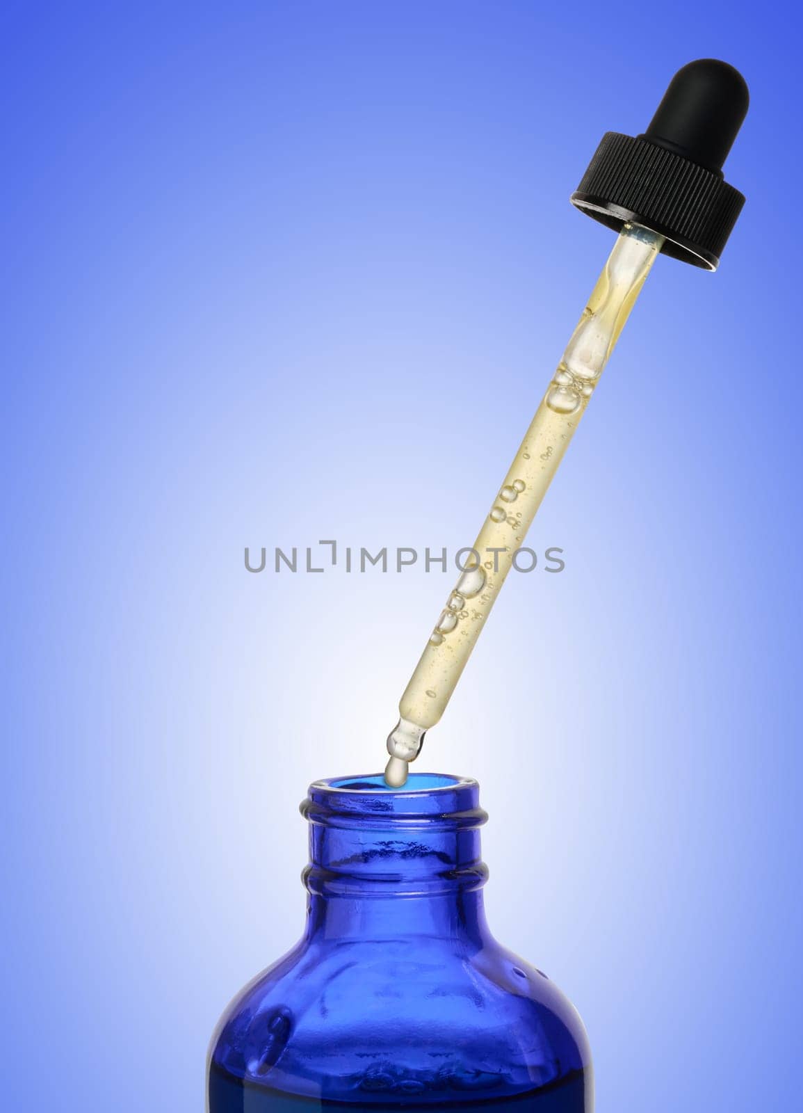 A glass blue bottle with a dropper on a blue background, a container for cosmetic products. 