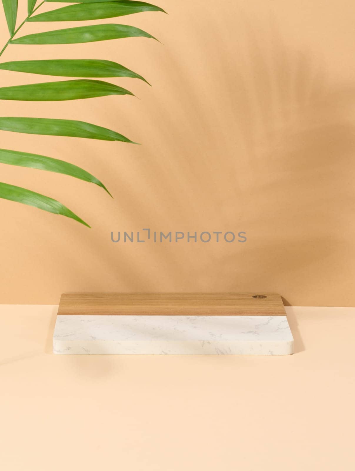 Wooden platform, shadow from a palm leaf on a brown background. Place for displaying cosmetics