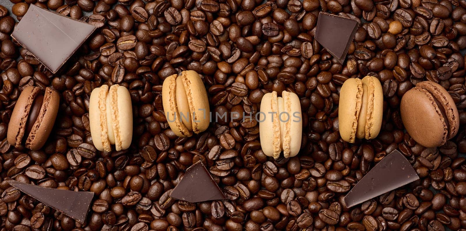 Multi-colored macarons on a background of coffee beans, top view by ndanko