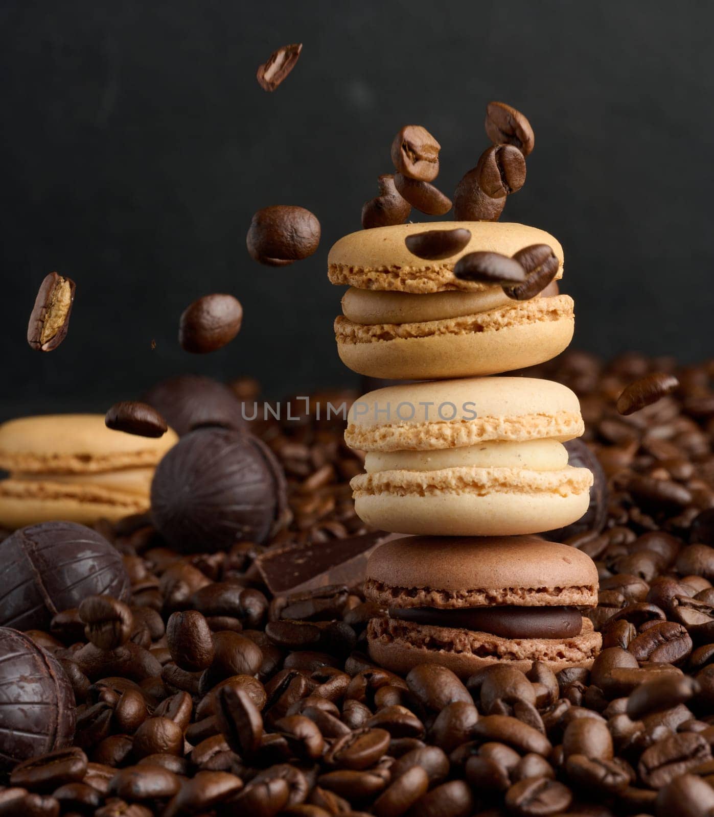 Stack of multi-colored macarons on a background of coffee beans, black background