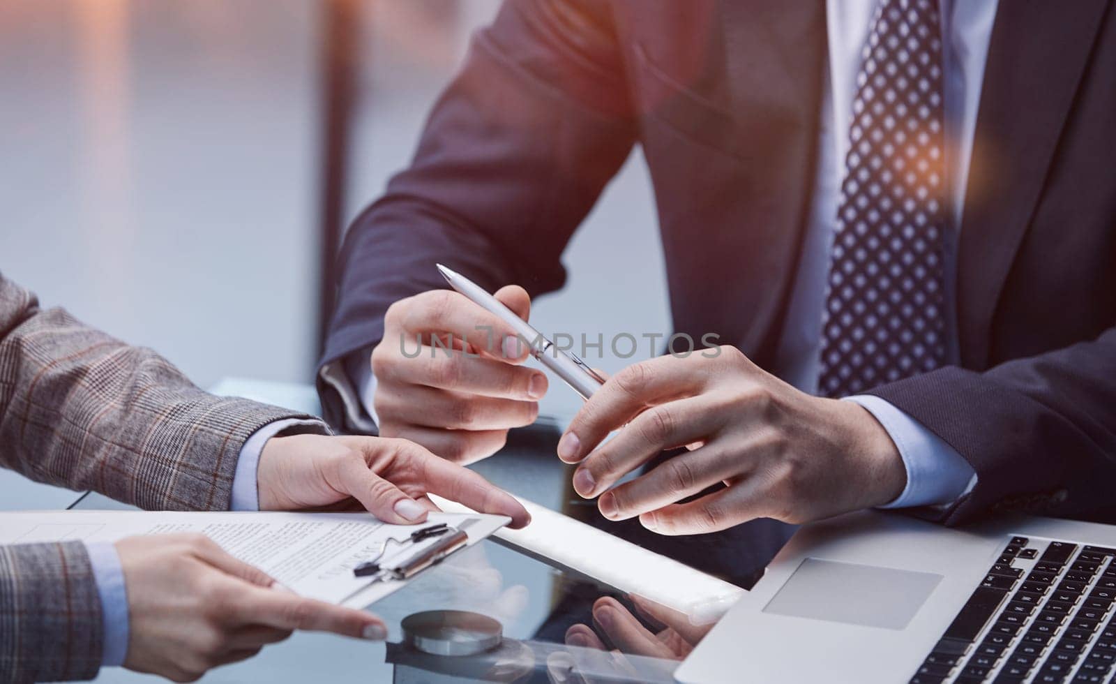 a man holding a ballpoint pen over documents close-up in front of a man in the foreground in the office. Conclusion business meeting concept. by Prosto