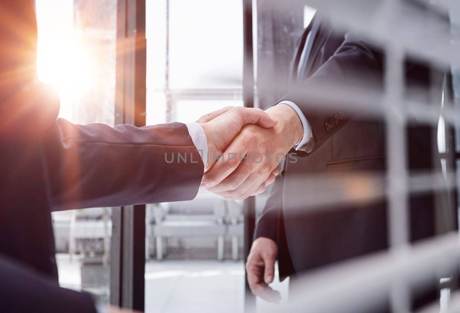 Two business people shaking hands in front of their colleagues