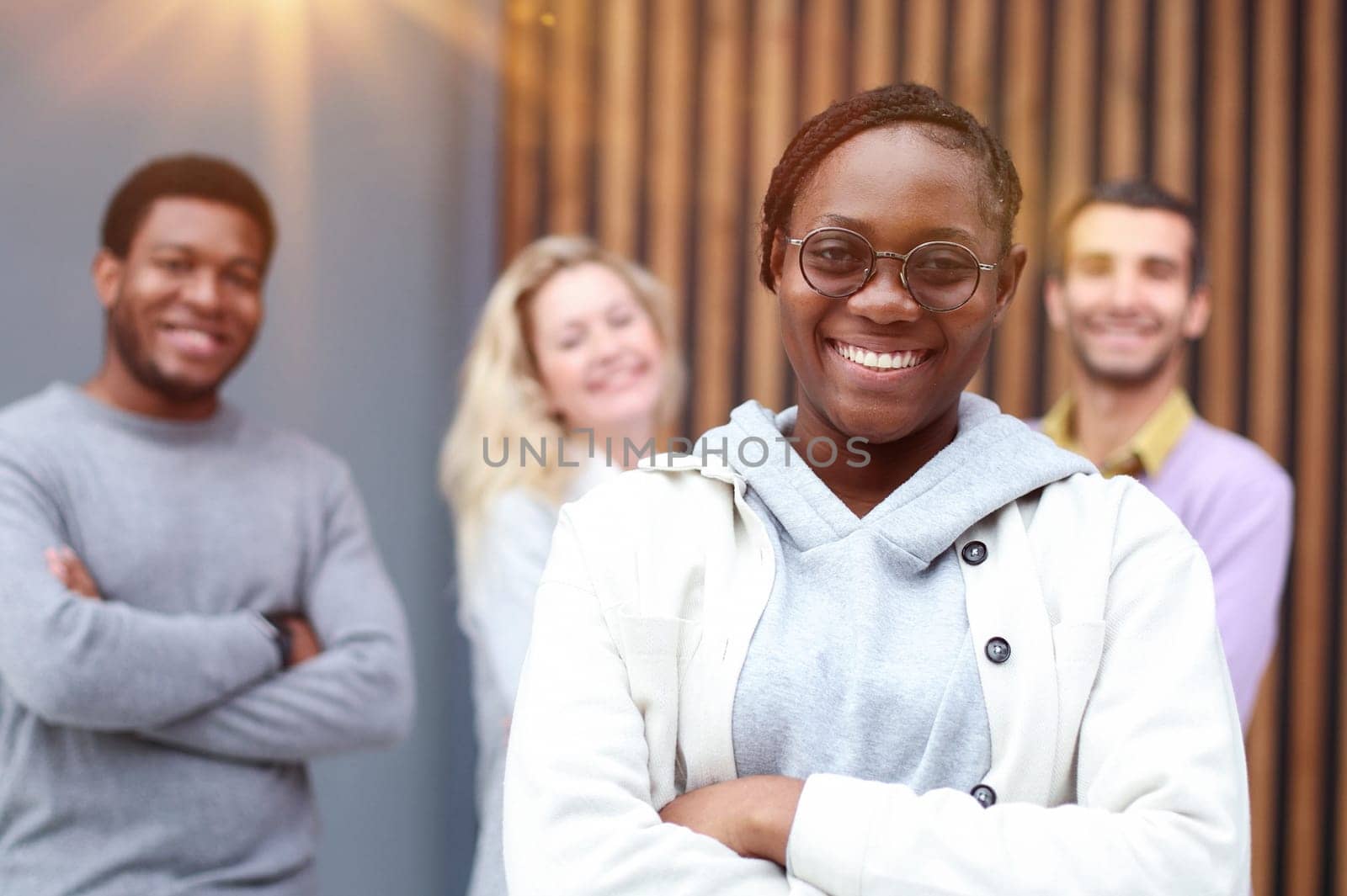 Young handsome editor is looking at the camera, acolytes are standing behind her