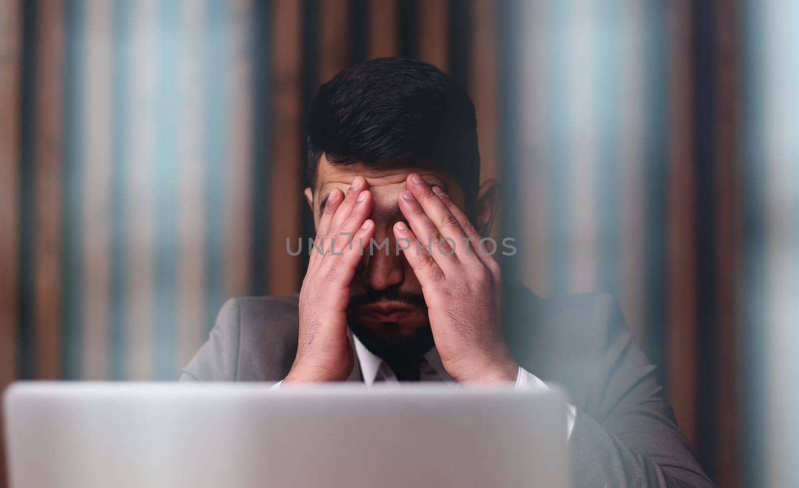 Tired man behind a computer screen from boring routine work in the office.