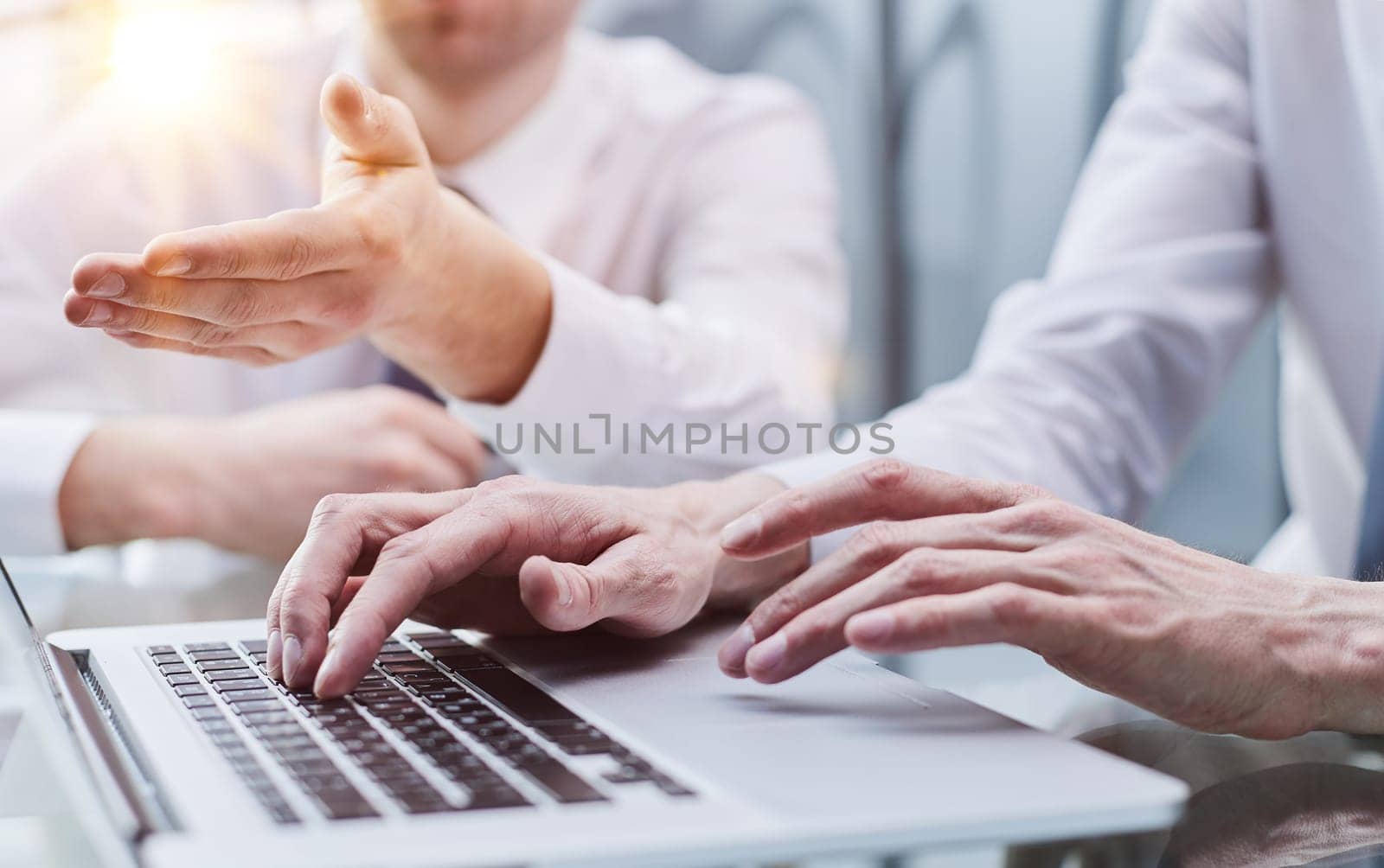 Closeup view of two young coworkers working on mobile laptop computer at office