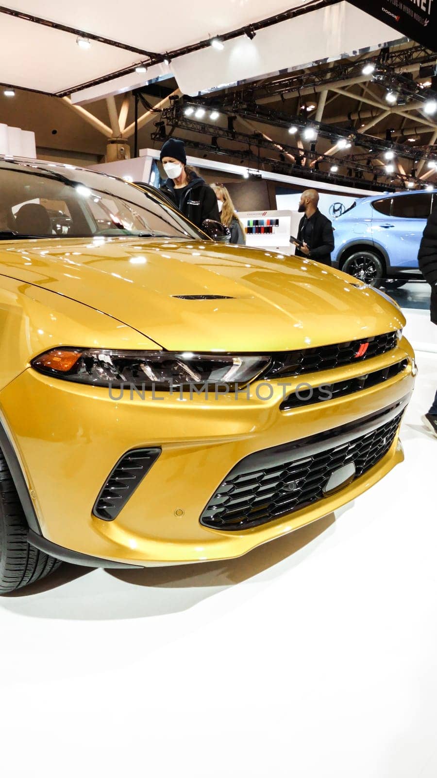 Close up view of yellow dodge GT car on display. Vertical. Crowds looking at new car models at Auto show. National Canadian Auto Show with many car brands. Toronto ON Canada Feb 19, 2023. by JuliaDorian