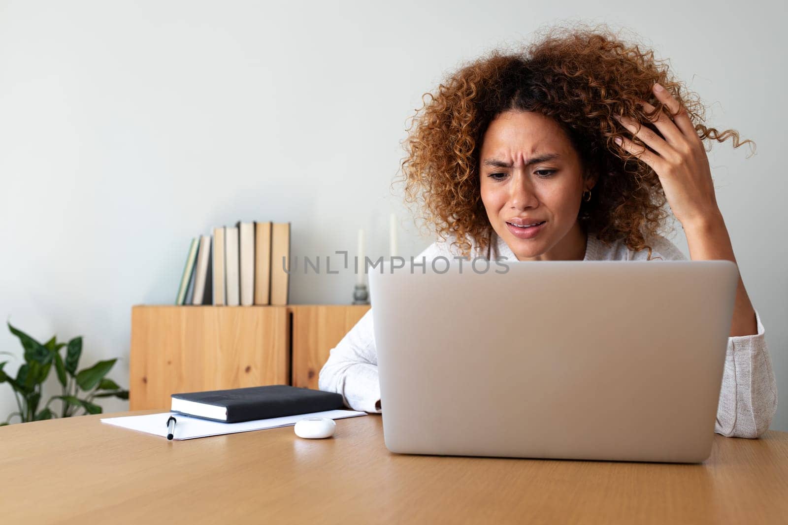 Multiracial hispanic woman feeling angry and frustrated while working with laptop at home office. Copy space. by Hoverstock