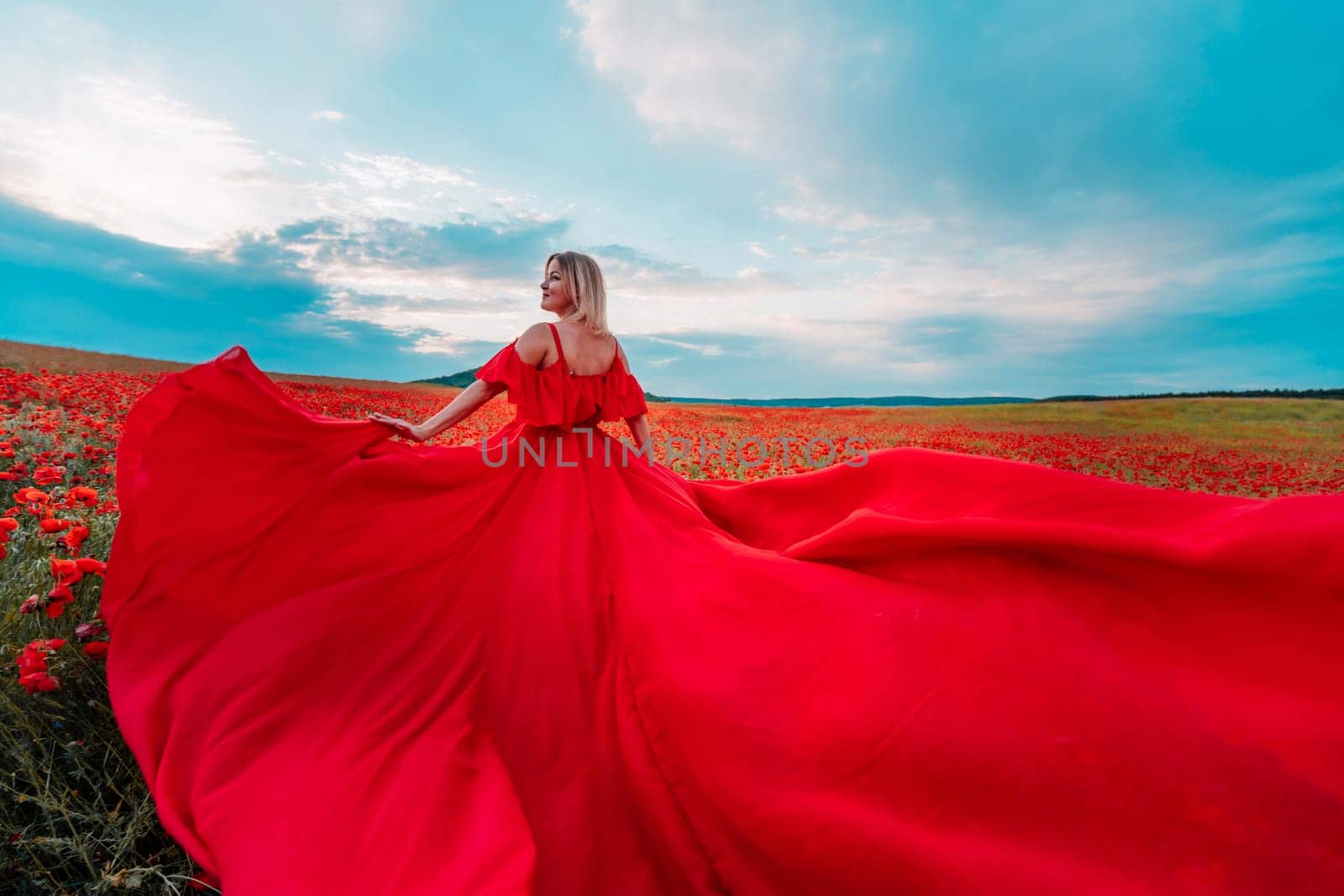 Woman poppy field red dress. Happy woman in a long red dress in a beautiful large poppy field. Blond stands with her back posing on a large field of red poppies by Matiunina