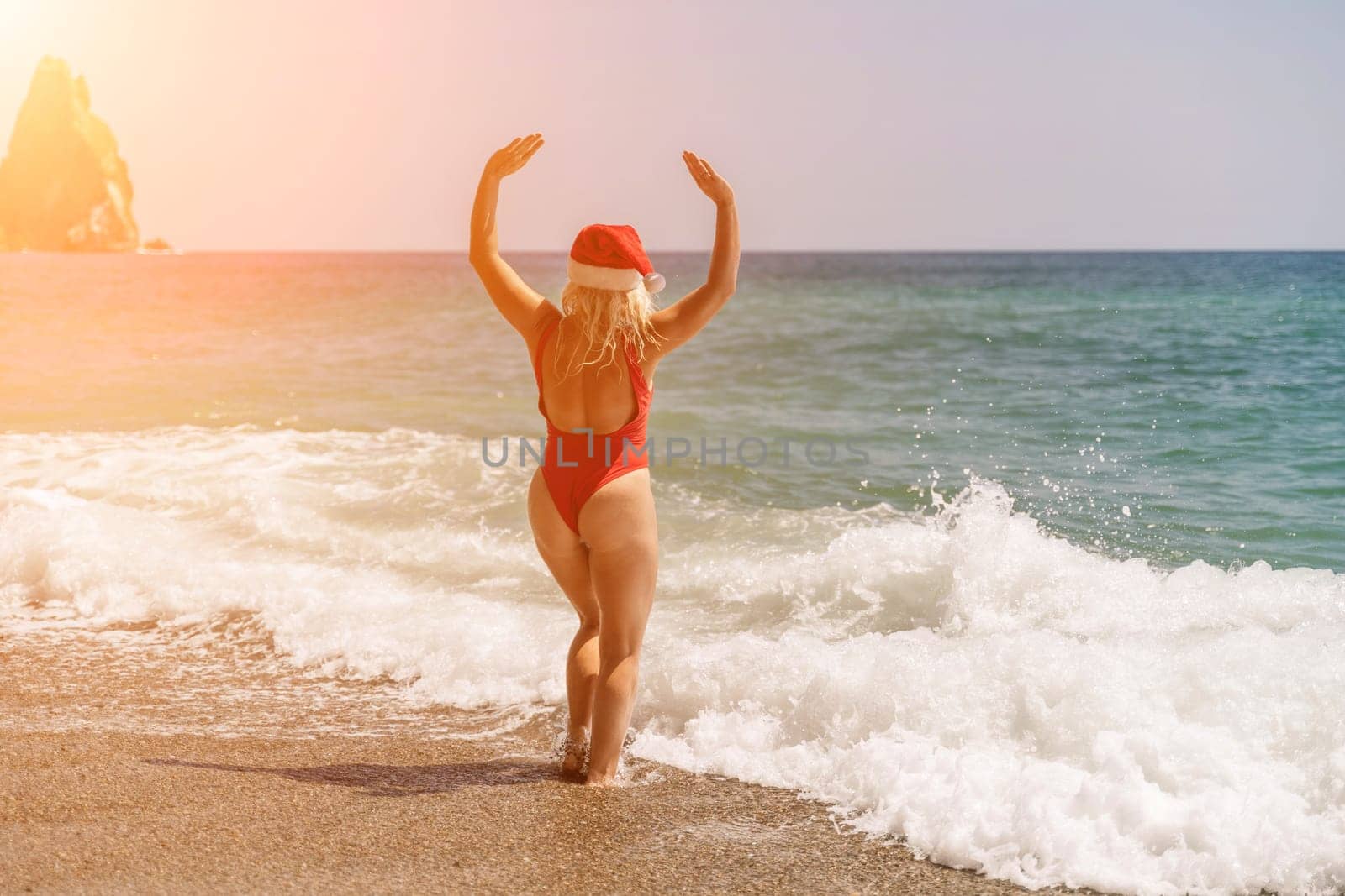 A woman in Santa hat on the seashore, dressed in a red swimsuit. New Year's celebration in a hot country by Matiunina