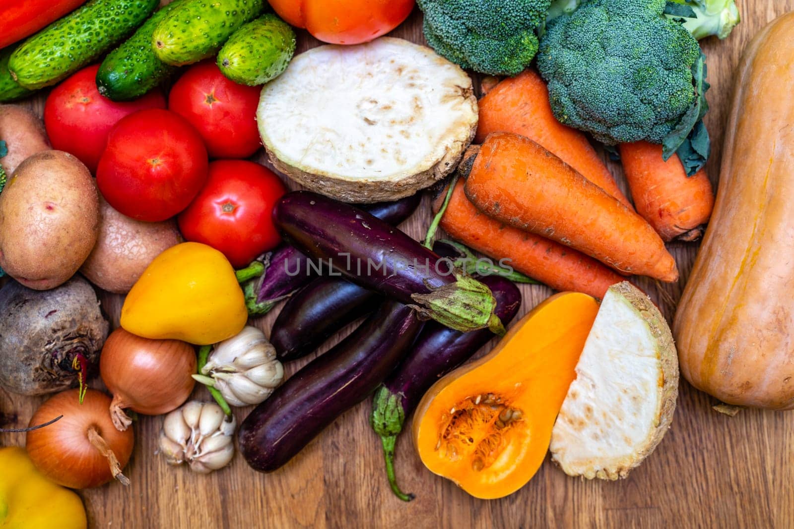 Various vegetables are laid out on a wooden table. Large assortment of vegetables food. pumpkin cabbage broccoli pepper tomatoes carrots and others by Matiunina
