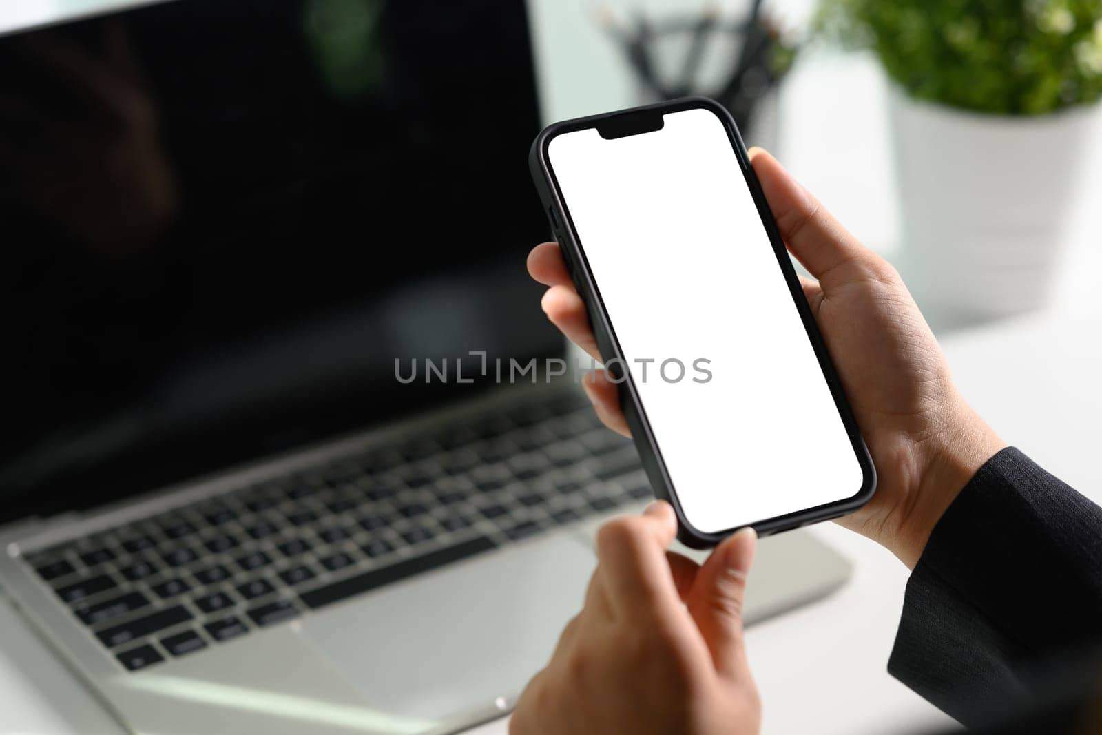 Cropped shot businessman using mobile phone at office desk. Empty screen for your text message by prathanchorruangsak