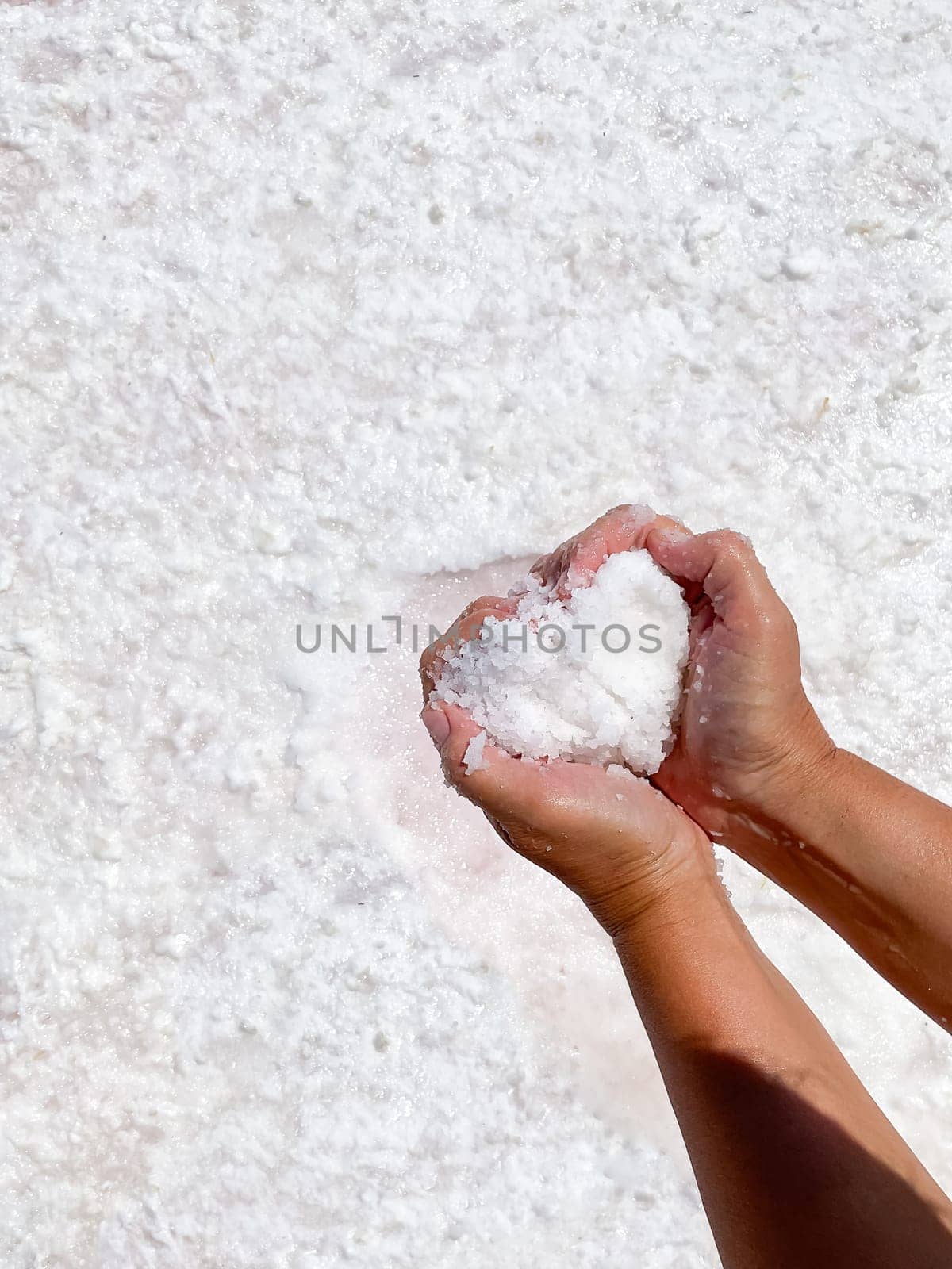 Womans hands with salt in her hands against the backdrop of salt lake. High quality photo