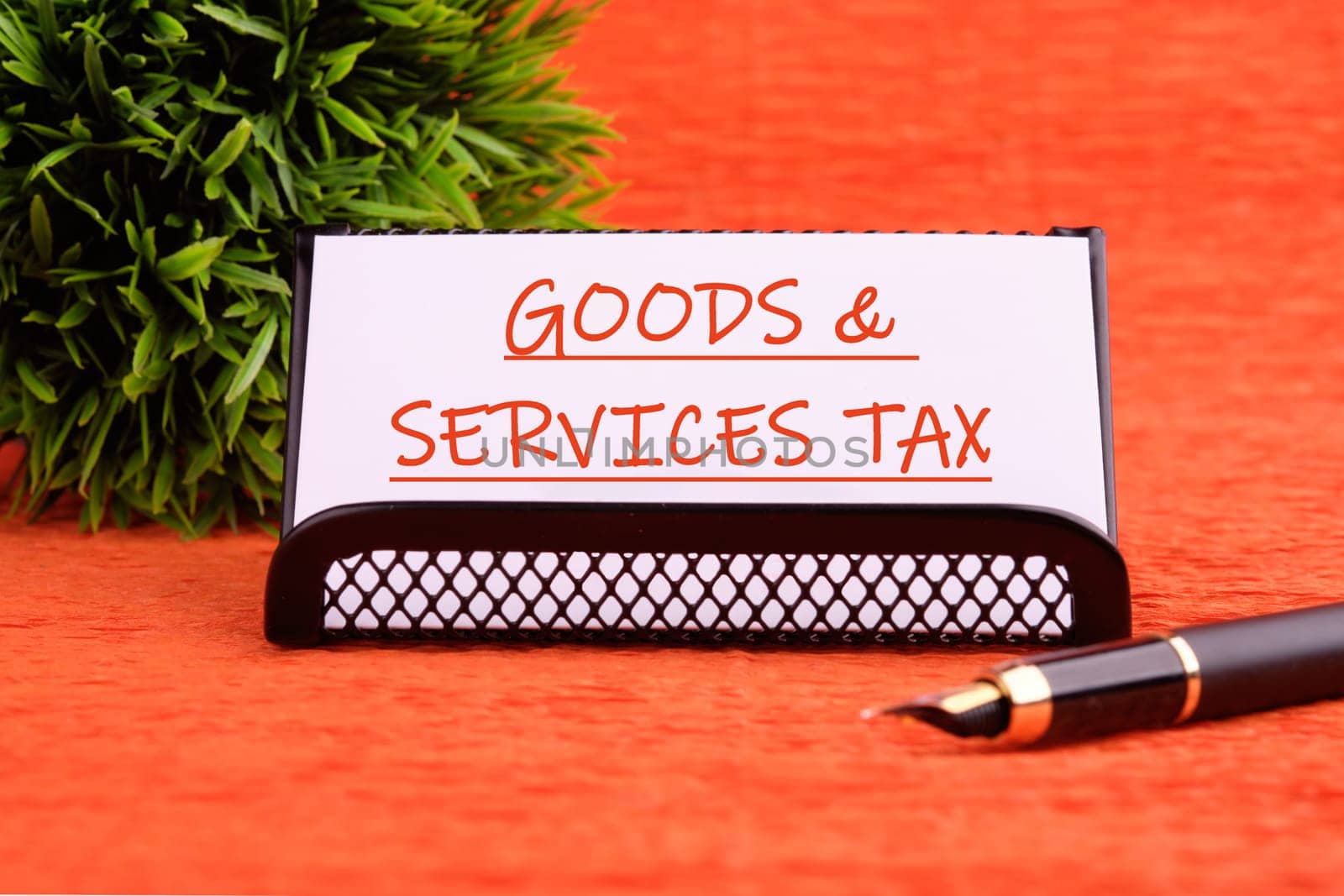 Goods and services and tax text written on a white card on a stand on an orange background