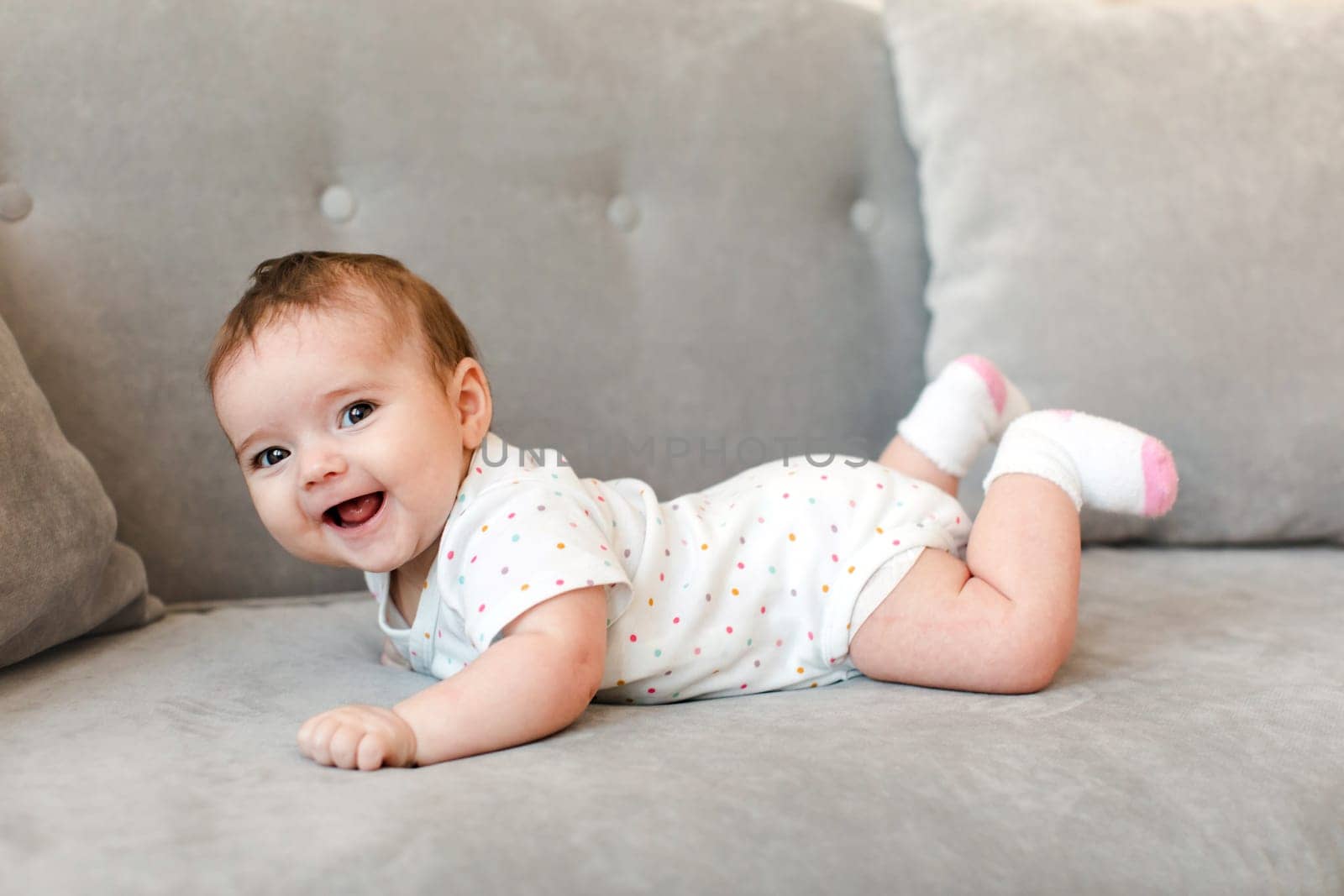 Happy baby lying on sofa and looking at camera at home by Demkat
