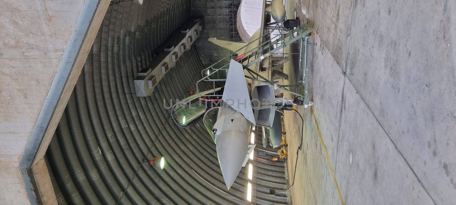 Istrana Italy December 13 2023: Vertical shot of a modern defense aircraft parked in an armored shelter, on alert for immediate takeoff. Perfect for editorial use with ample copy space.