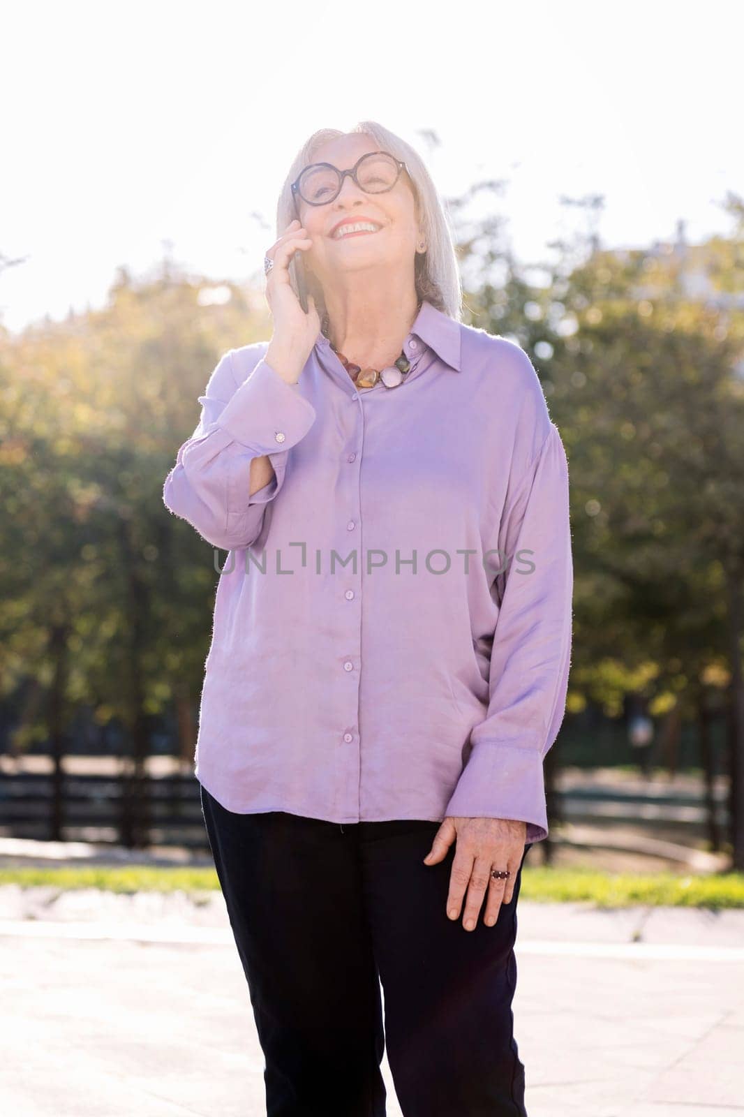 senior woman smiling happy talking by mobile phone outdoors, concept of technology and elderly people leisure