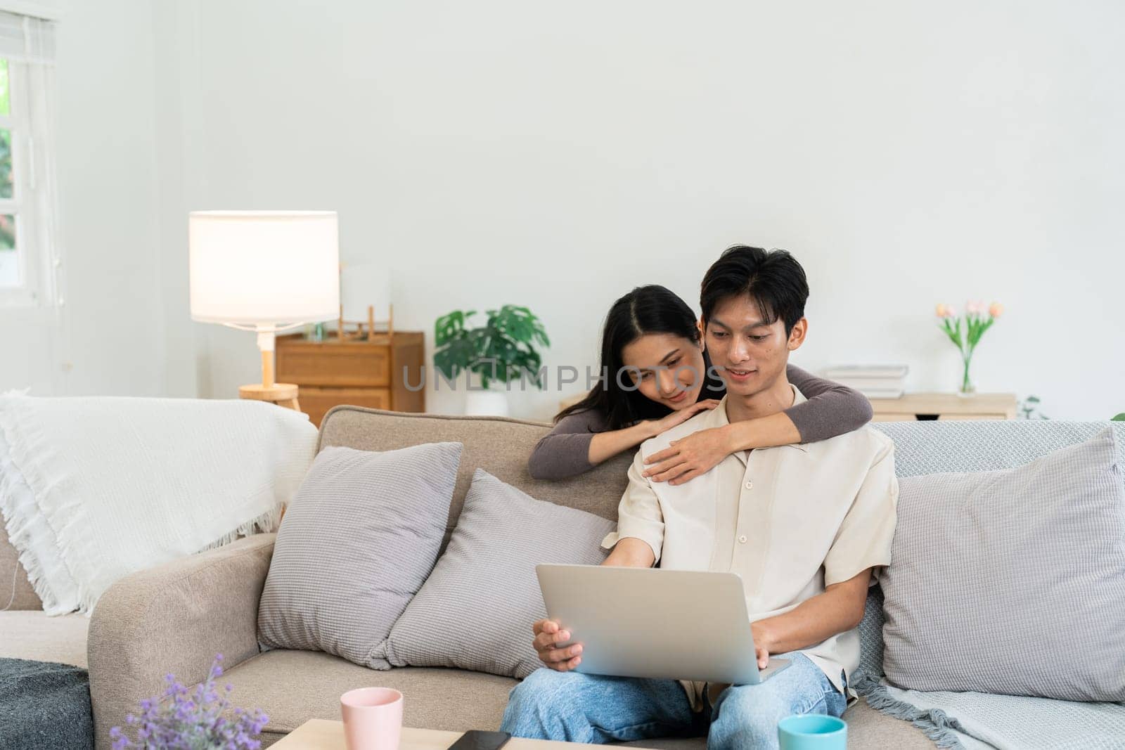 Happy young couple looking laptop relax on sofa in living room watch video on laptop together by itchaznong