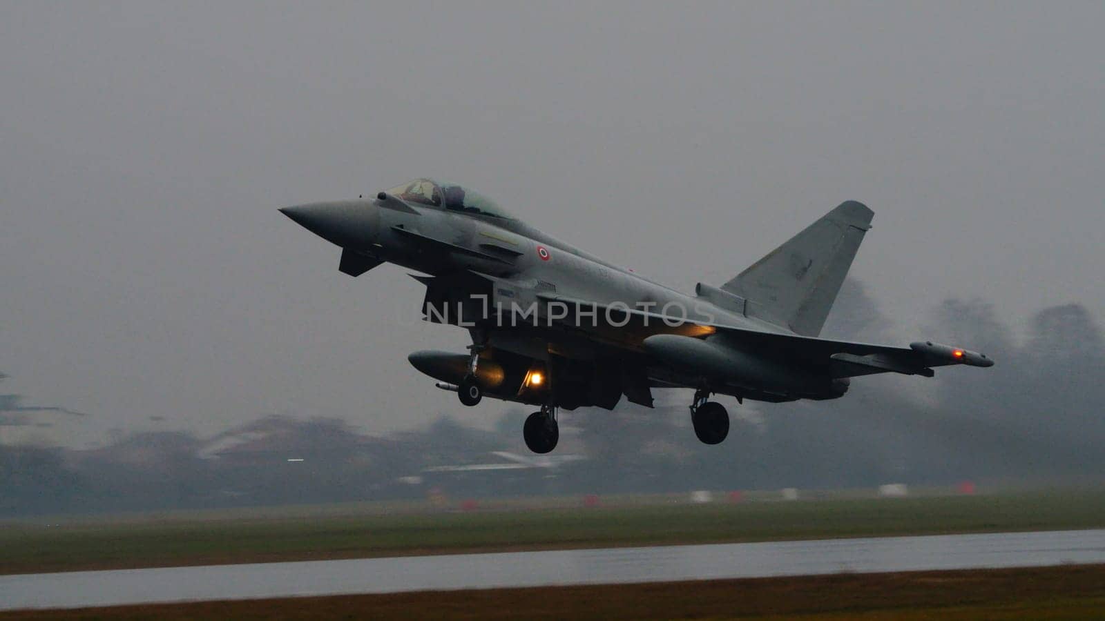 Istrana Italy December 13 2023: Combat aircraft lifts off a flooded runway, casting massive water clouds. Includes copy space. NATO air defense capability in all weather. Copy Space.
