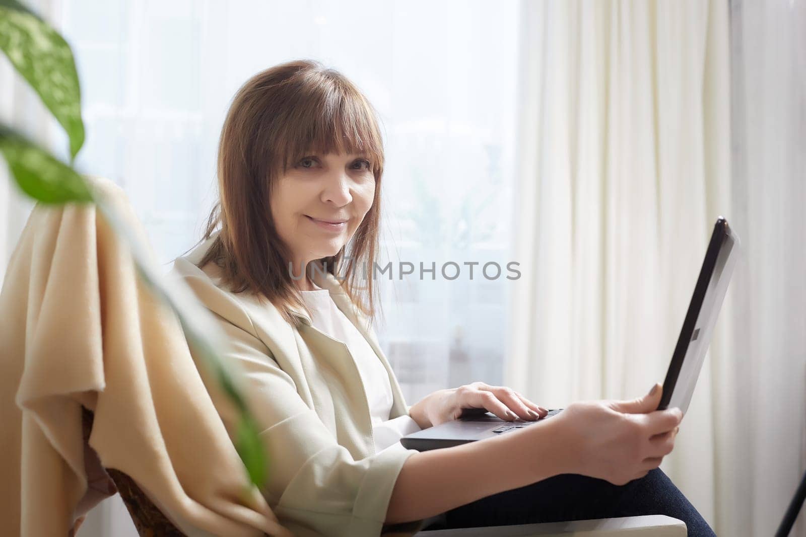 Elderly lady with a laptop in the room. A businesswoman is a leader, a manager is working. Grandma communicates with her grandchildren on the Internet