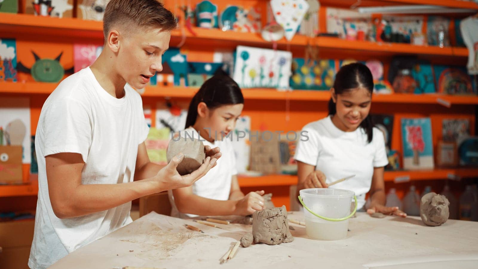 Smart student using hand press on clay piece at pottery workshop. Edification. by biancoblue