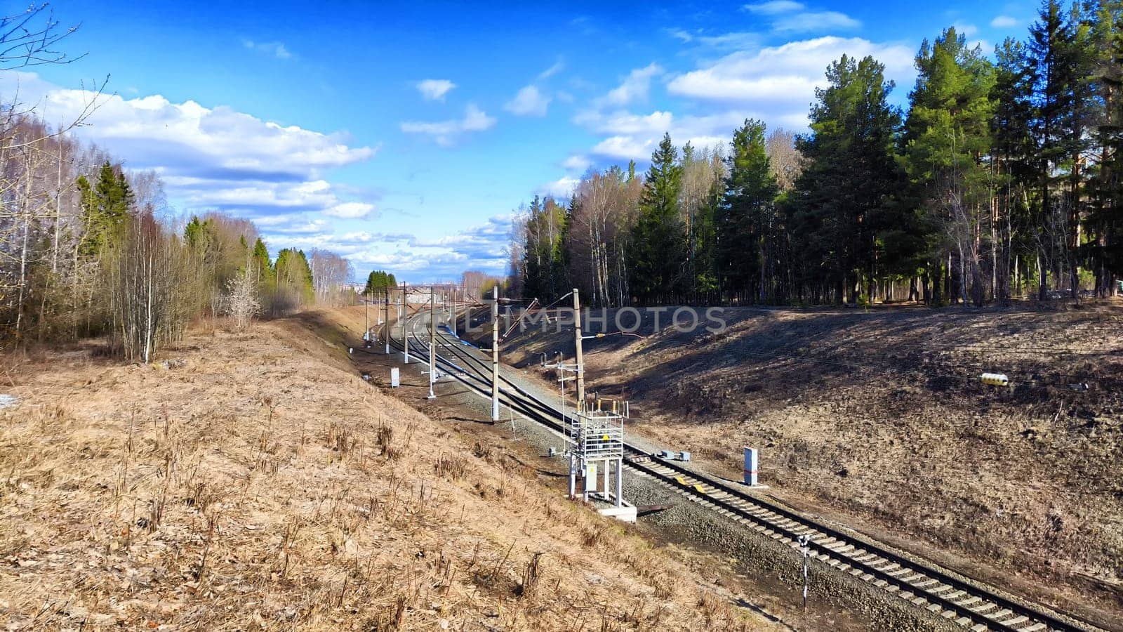 Railway track in the spring forest with blue sky. Concept of travel and trip