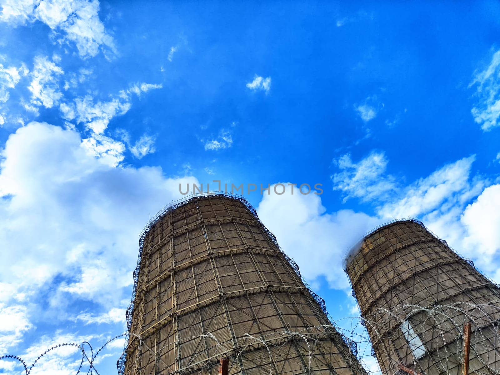 Big tower of CHPP close-up. White steam from wide pipe of CHP and blue sky. Industrial background. Huge pipes of thermal power plant produce steam for electric power. Strategically important object