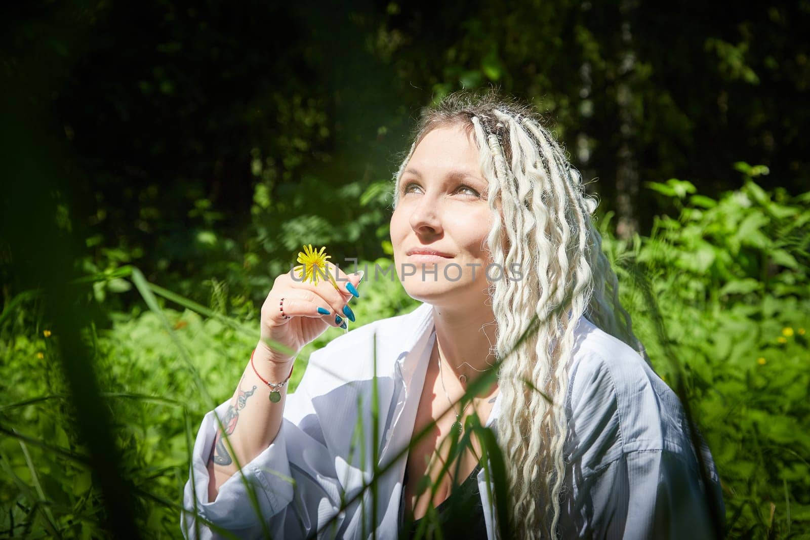 Kirov, Russia - June 12, 2023: Hippy girl enjoys life in forest on a sunny spring or summer day. Woman in green nature landscape