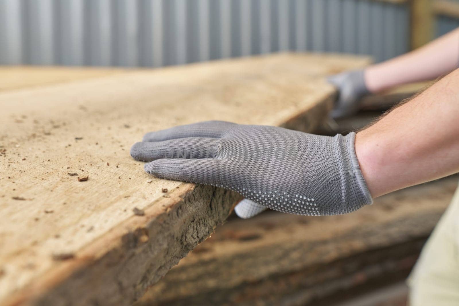 Close-up of carpenters hands with plank wood at carpentry woodworking workshop