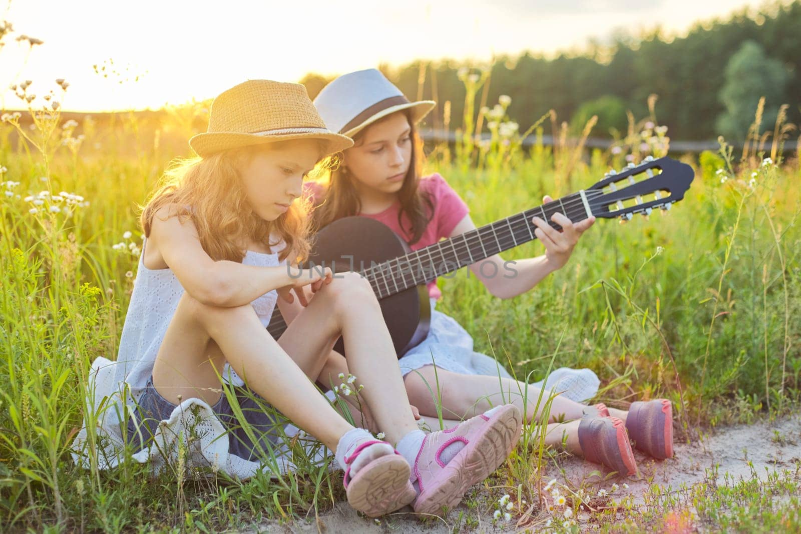 Children sitting in nature with classical guitar by VH-studio