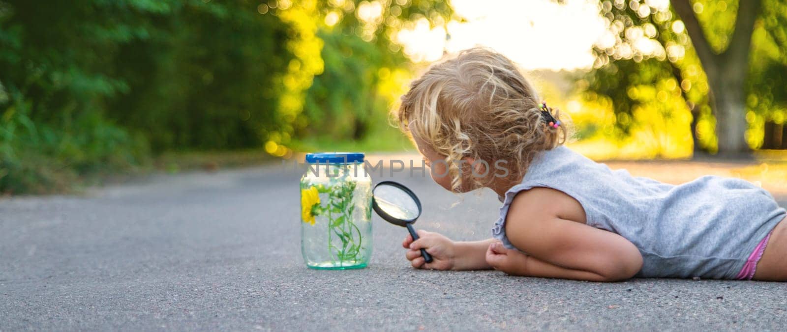 A child looks into a jar with a magnifying glass. Selective focus. Kid.