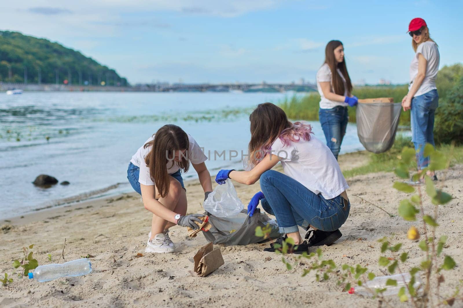 Group of students with teacher in nature doing cleaning of plastic garbage. Environmental protection, youth, volunteering, charity, and ecology concept