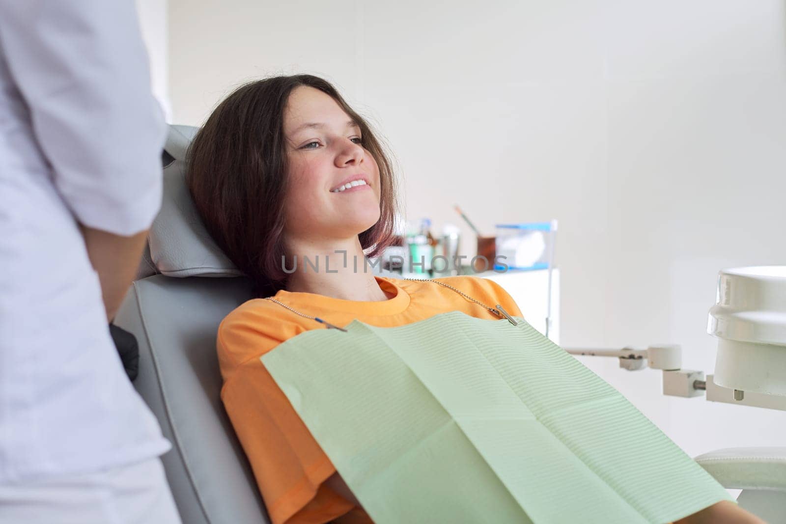 Young girl treating teeth, female teenager sitting in dentists chair by VH-studio