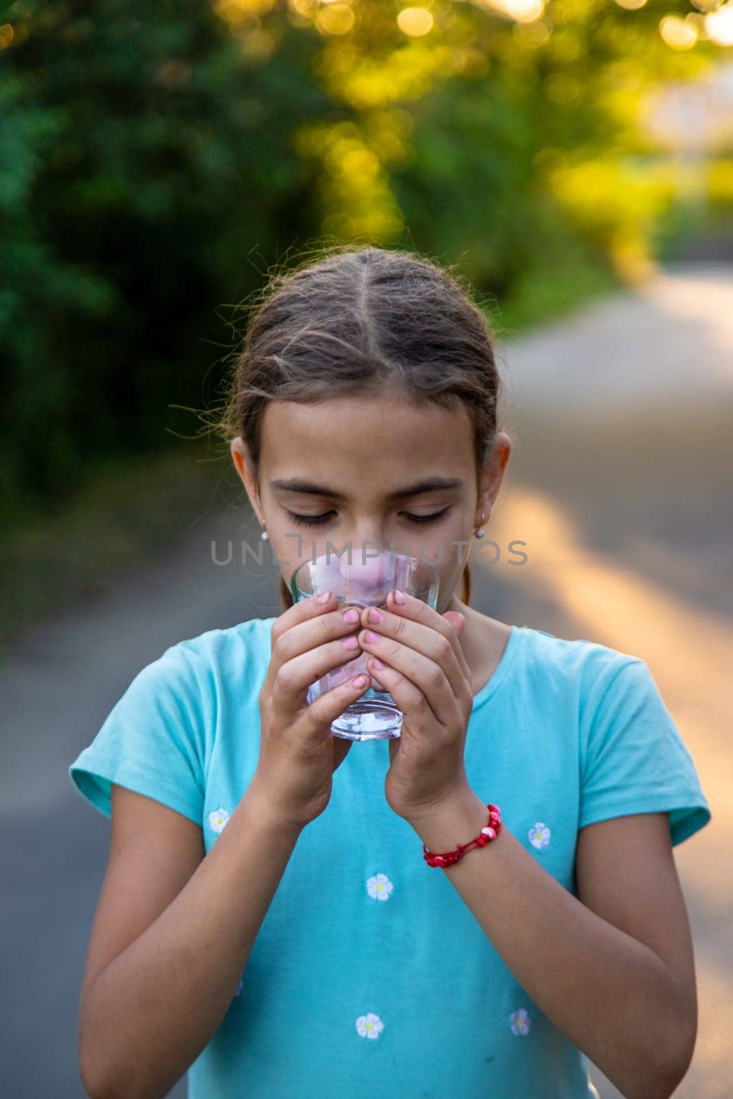 A child drinks water from a glass. Selective focus. by yanadjana