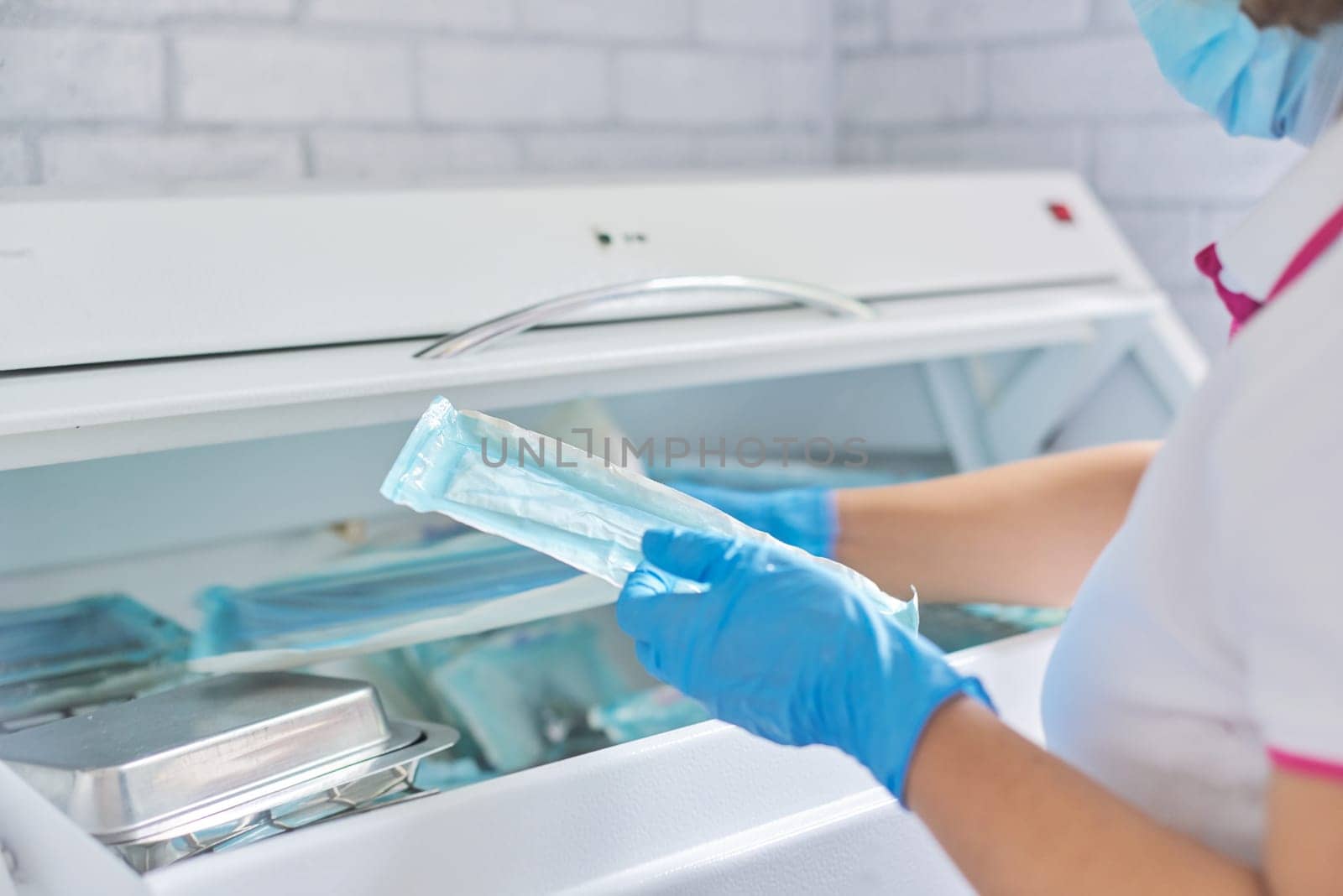 Female nurse doing sterilization of dental medical instruments in autoclave by VH-studio