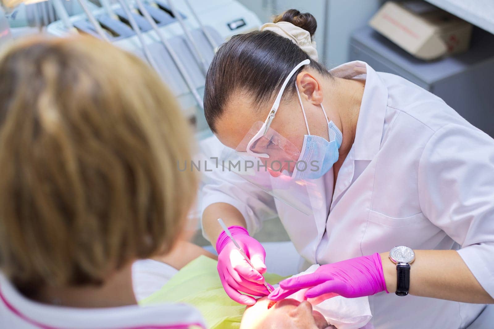 Doctor dentist with assistant treating teeth to a patient in dental clinic. Dentistry, healthy teeth, sedation, medicine and healthcare concept