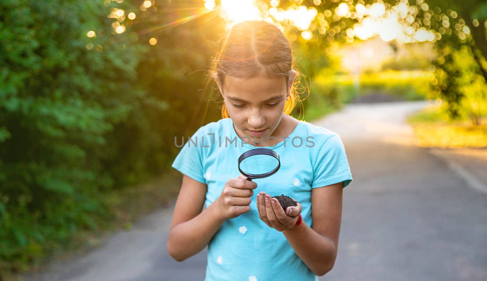 The child looks at the soil in his hands with a magnifying glass. Selective focus. Kid,