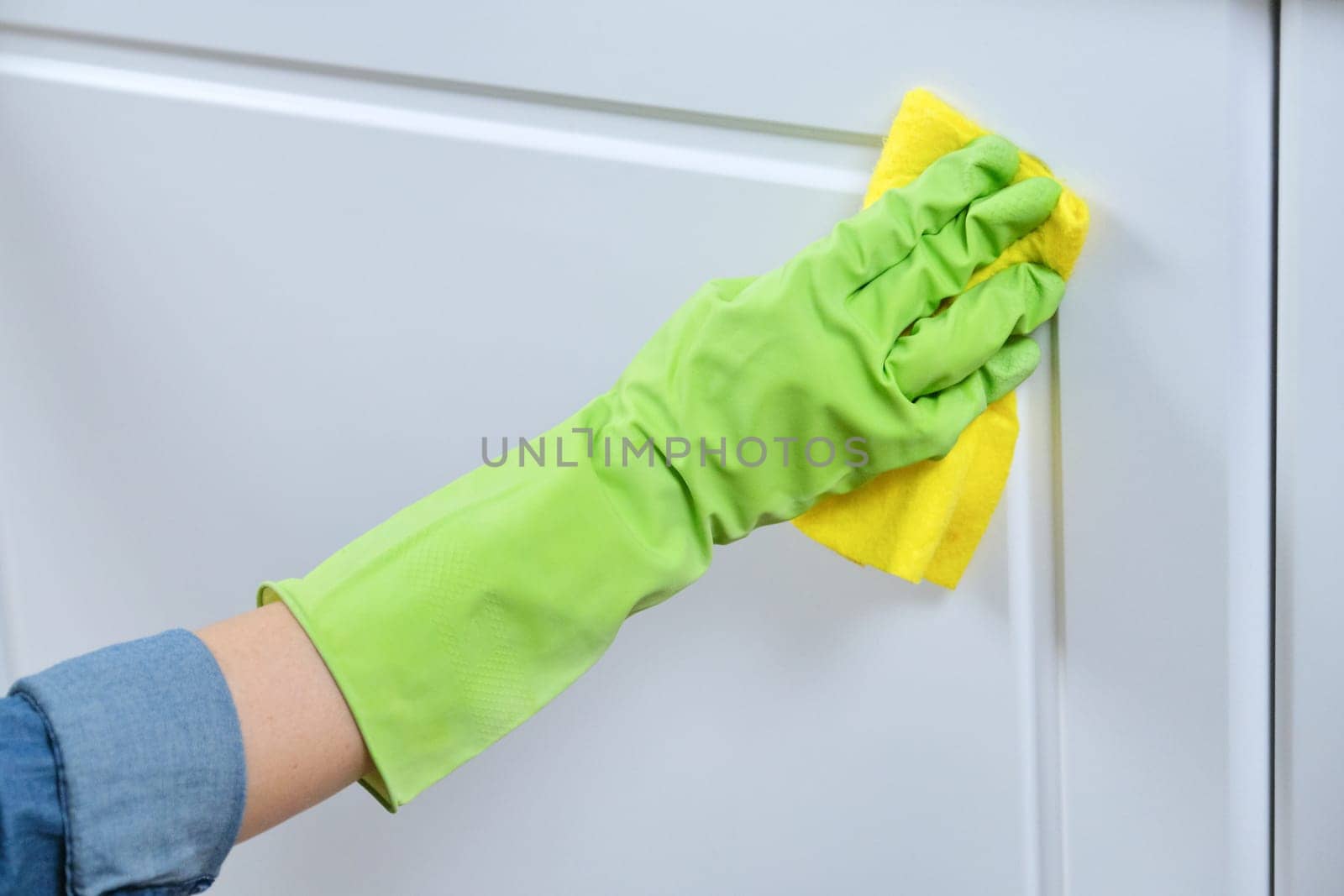 Woman in gloves with rag washing, cleaning, polishing furniture doors by VH-studio