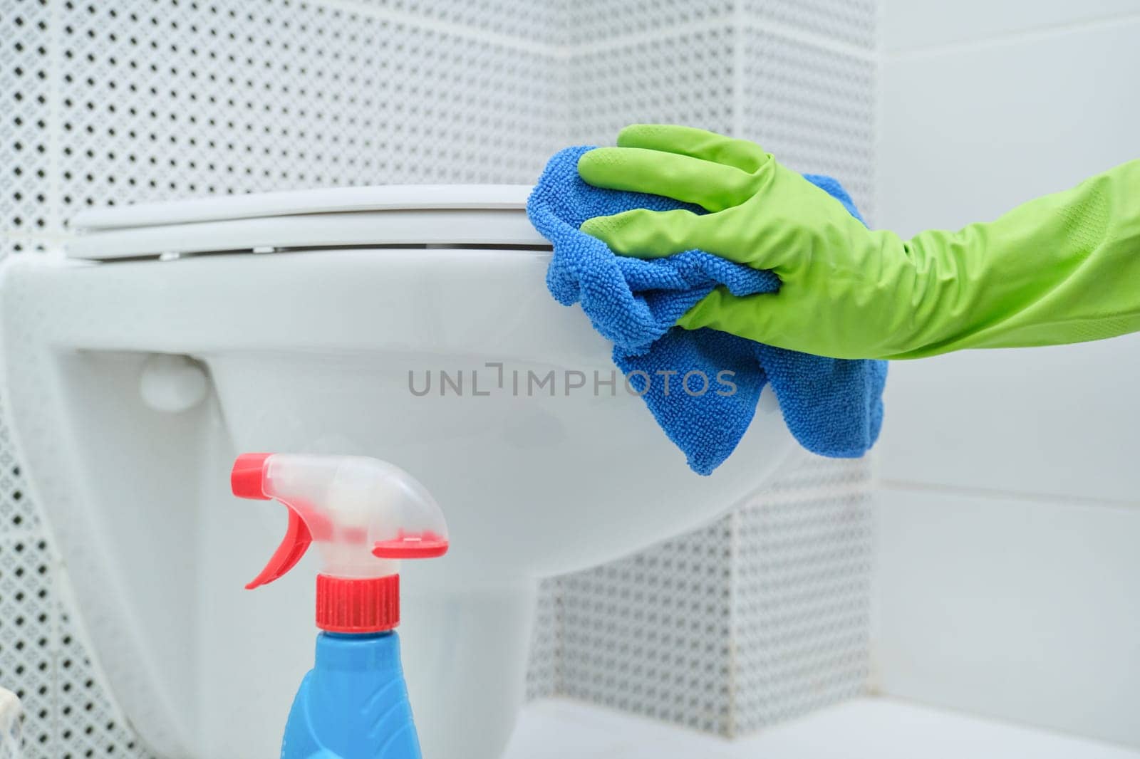 Close-up of hand in gloves with rag and detergent washing hanging toilet by VH-studio