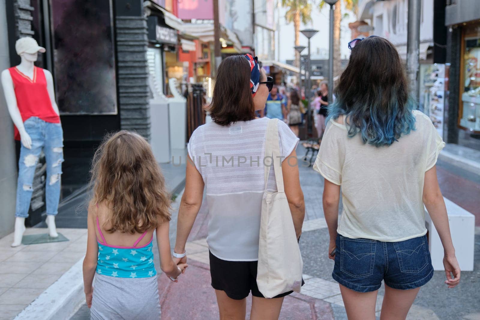 People walking along street of small resort town, back view by VH-studio