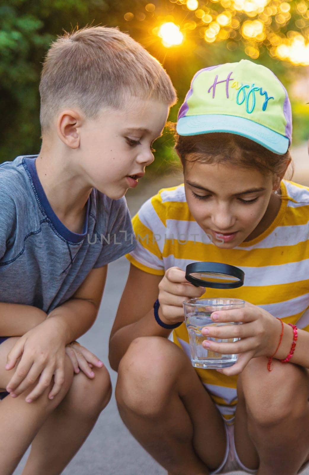 Children look with a magnifying glass into a glass of water. Selective focus. Kid.