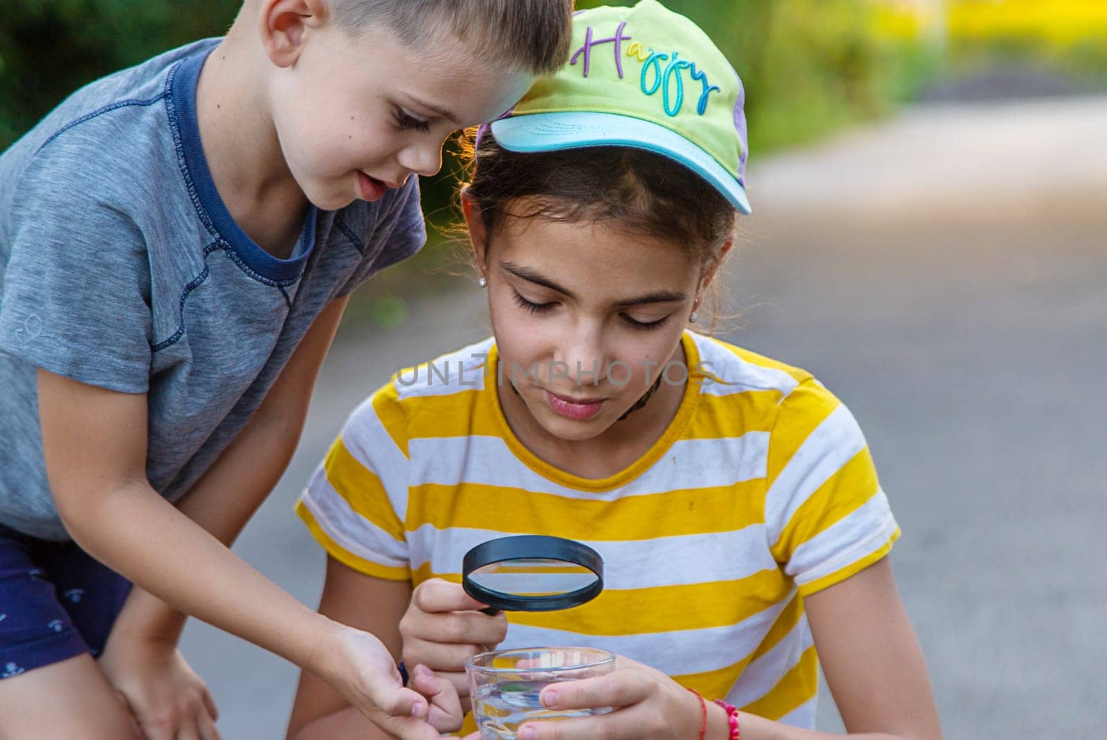 Children look with a magnifying glass into a glass of water. Selective focus. Kid.