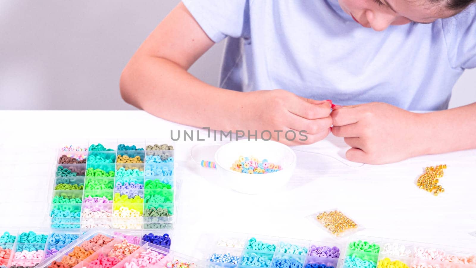 Delicate fingers of a young girl navigate through a treasure trove of bright, multicolored beads, each compartment revealing a new hue to choose from.