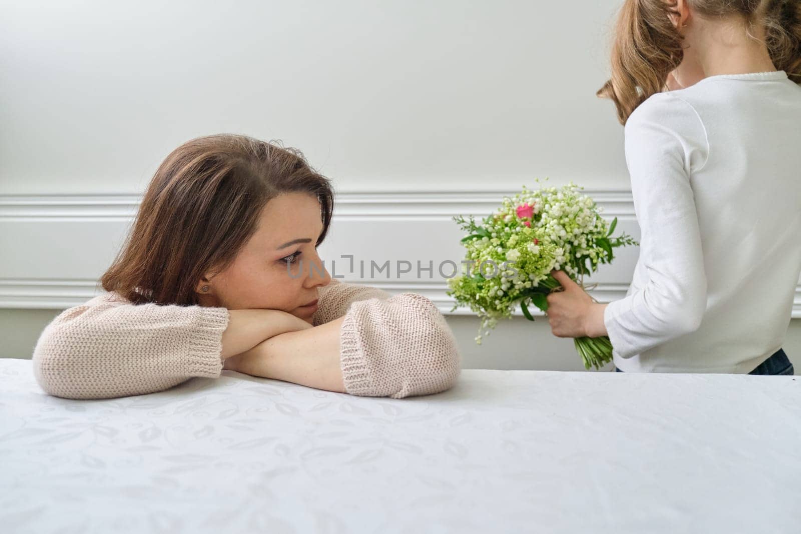 Emotional photo of mother and daughter, girl with bouquet of flowers covered her face. woman with serious face, conflict of parent and child