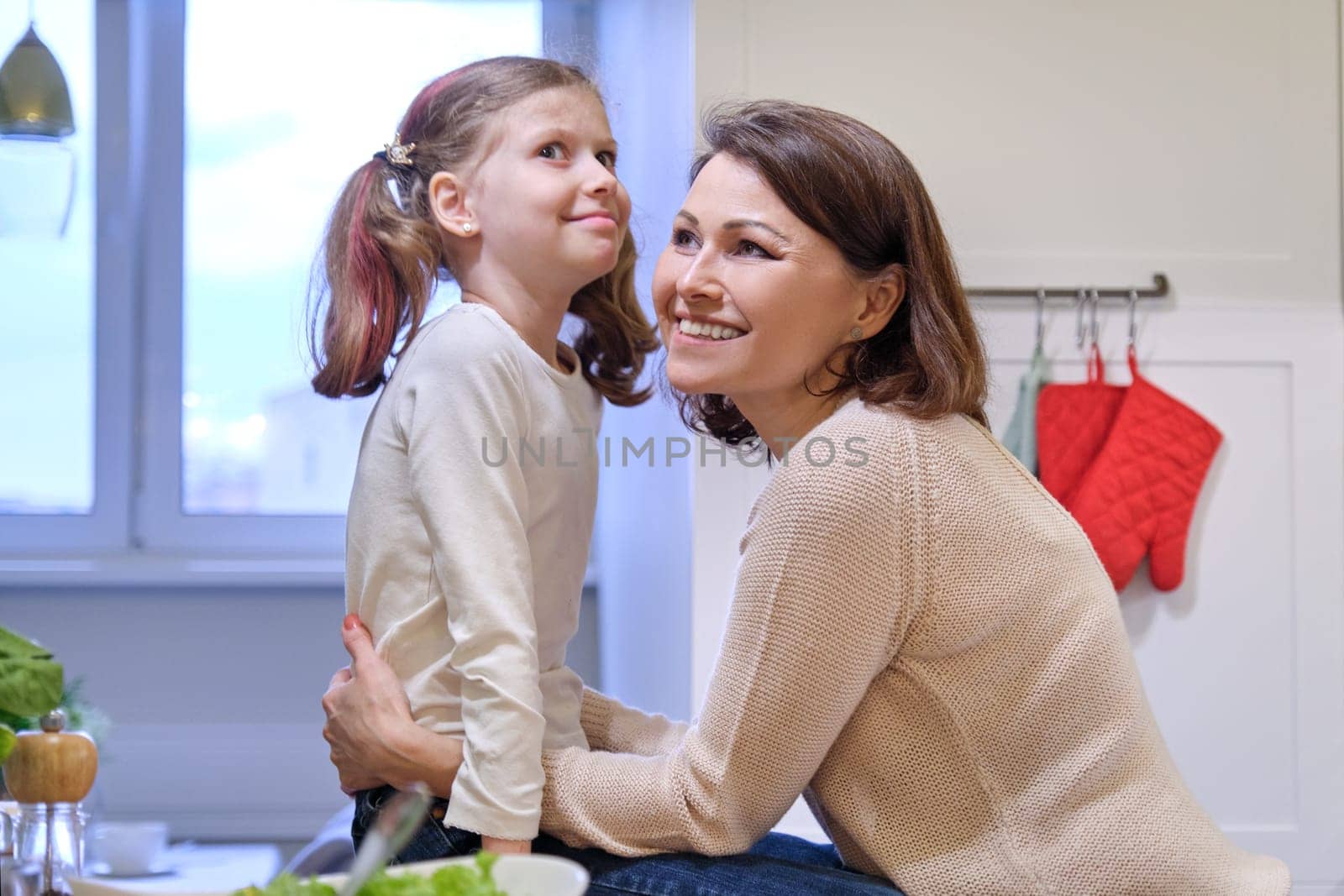 Happy mother and daughter child talking laughing in kitchen, cooking together, relationship parent and child 9,10 years old