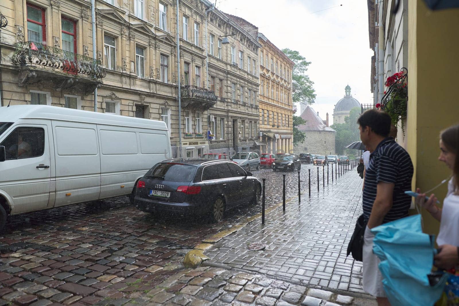 Lviv, UA, 05-08-2019. Old European city in the rain, street with driving cars. End of summer, beginning of autumn.