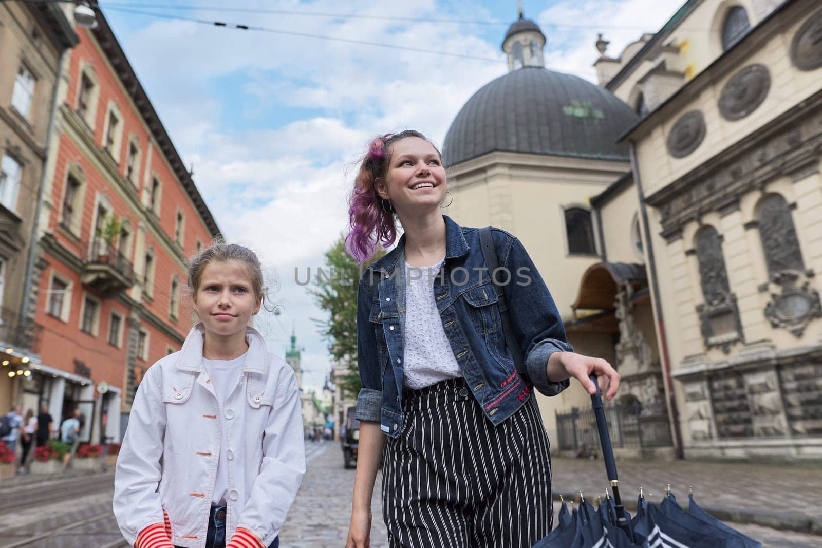 Two girls walking on the street of tourist European city.