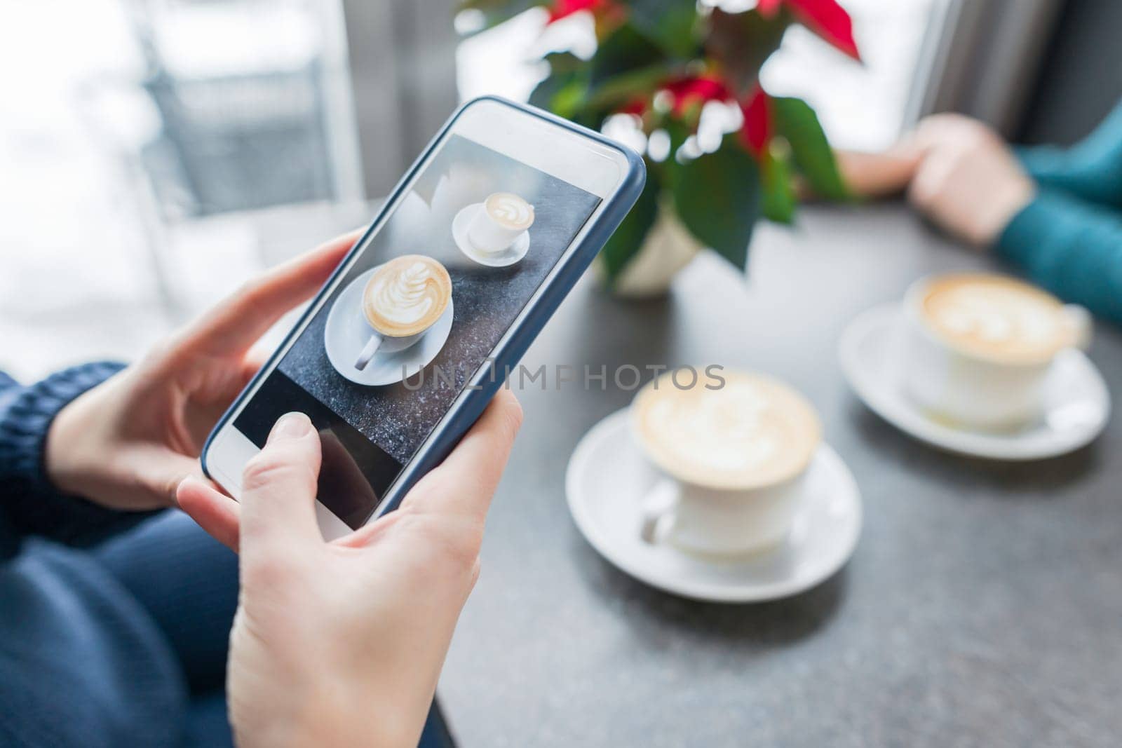 Coffee art, hands of woman taking photos on the phone two cups with latte art, background gray stone surface of the table coffee shop