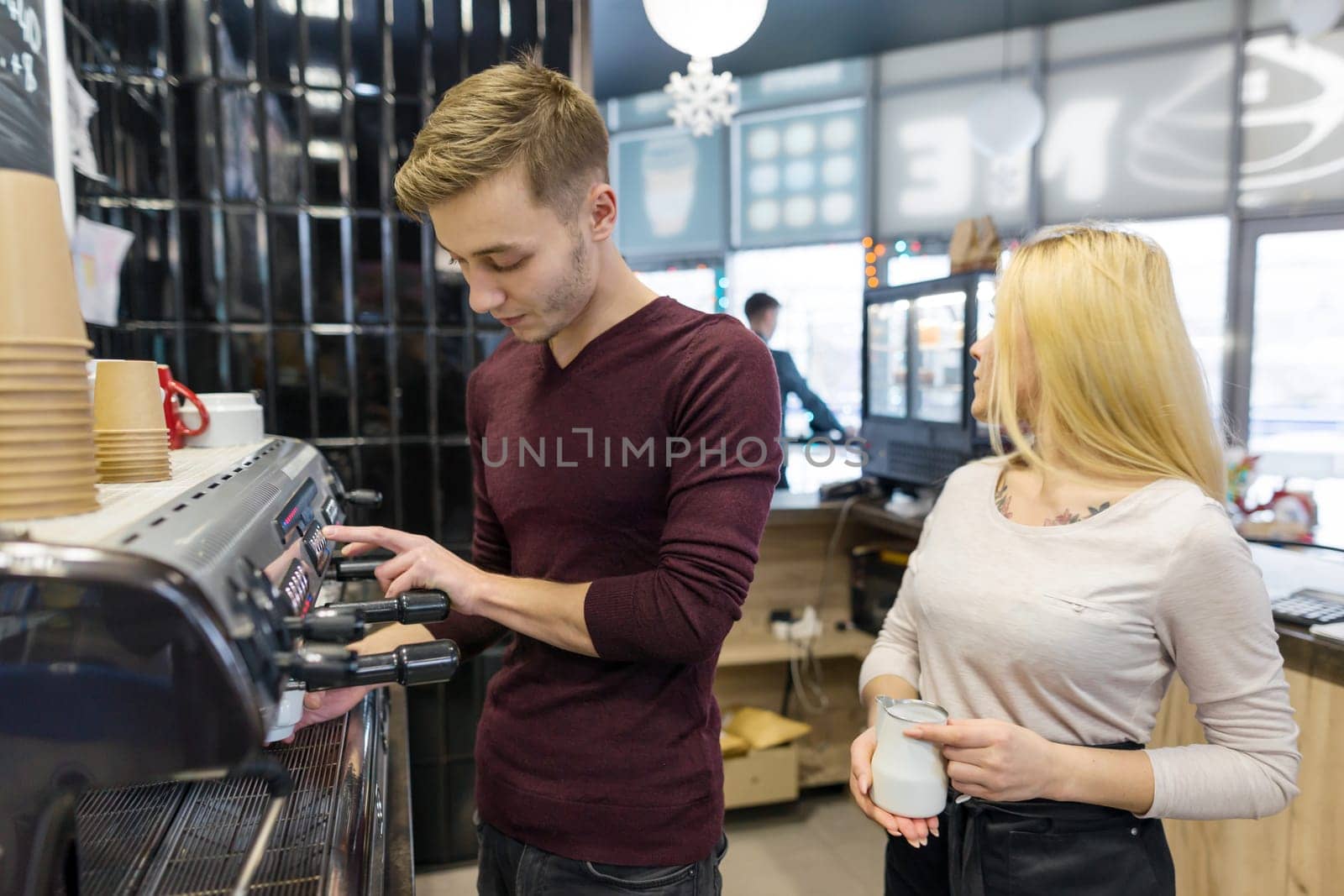 Barista man and woman making coffee, couple of young people working in coffee shop.