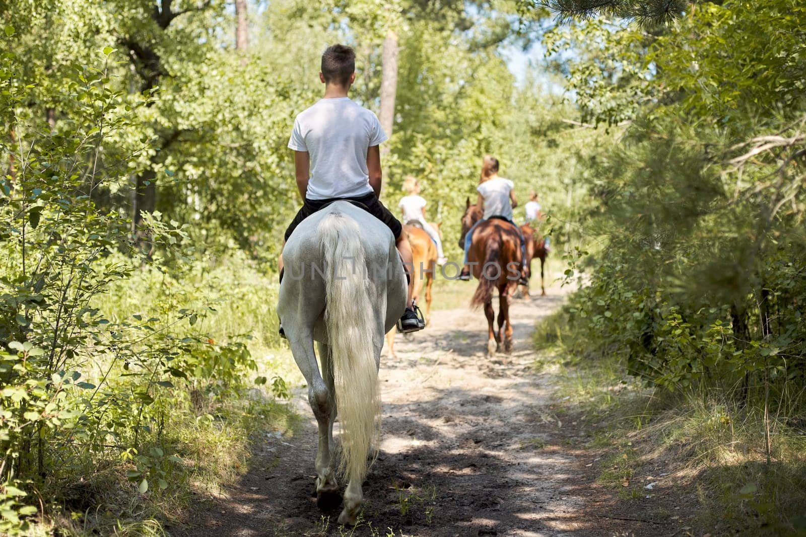 Group of teenagers on horseback riding in summer park by VH-studio