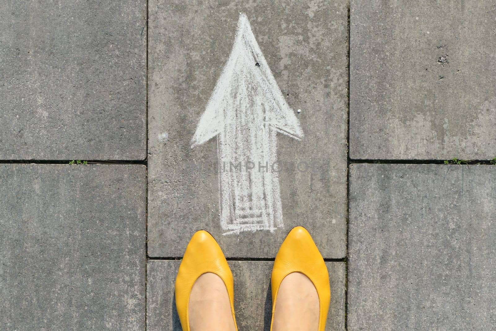 Arrow sign painted on gray sidewalk with womens legs, top view by VH-studio